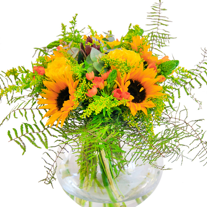 The first impression of this captivating bouquet is an exuberance akin to early autumn mornings in West Norwood-sunlit, abundant, and full of promise. Majestic sunflowers, their chocolate-brown centers rich and inviting, form the crown of the arrangement, encircled by spiraling yellow roses whose buttery petals echo the gentle glow of sunrise over York Hill. Between these blooms, scarlet Hypericum berries glimmer with lively energy, introducing playful pops of color and gleaming like street cafe lights on a summer's evening. The bouquet is woven with a tapestry of greenery: airy solidago sprigs and feathery ferns spill over the rim like the lush foliage along West Norwood's quiet paths, while eucalyptus leaves in soothing bluish-green offer a peaceful aromatic note in the ensemble. All elements are anchored within a graceful, fishbowl-style glass vase, its smooth transparency offering a glimpse into the tangle of stems and crystal-clear water below-a hallmark of freshness ensured by local expertise. As sunlight filters across the bouquet, the interplay of hues brightens any room, evoking a sense of happiness and togetherness. With its harmonious blend of colour, texture, and form, this bouquet embodies the welcoming heart of West Norwood-a gift as suitable for birthdays, anniversaries, or cheerful everyday surprises as it is for transforming home or office spaces into havens of natural beauty.
